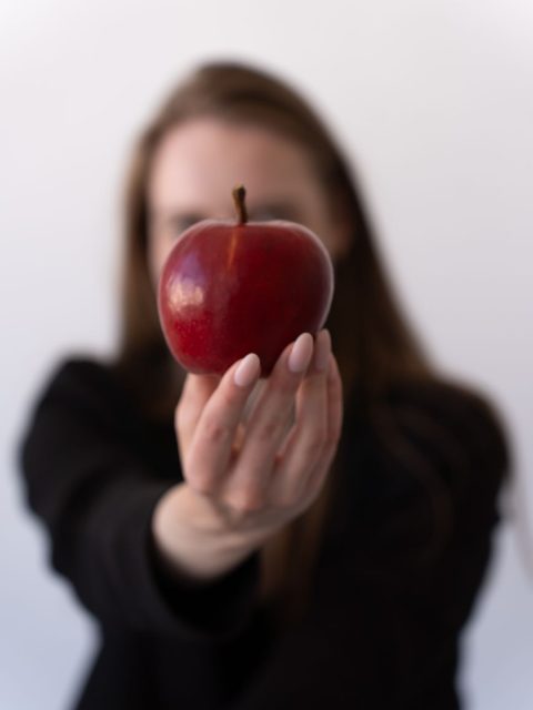 woman holding fresh red apple with blurred face