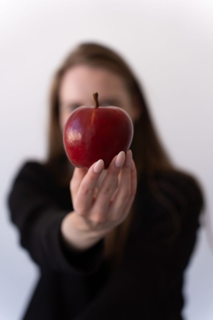woman holding fresh red apple with blurred face
